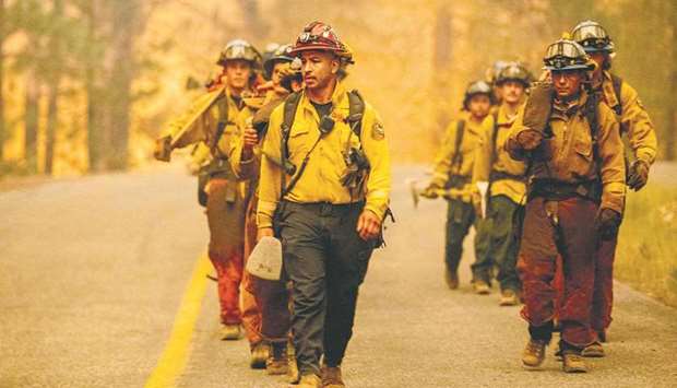 A crew of firefighters walk along a road while working the scene during the Dixie fire in the Prattville community of unincorporated Plumas County on Friday. The Dixie fire, which started only a few miles from the origin of the deadly Camp fire, has churned through more than 150,000 acres. (AFP)