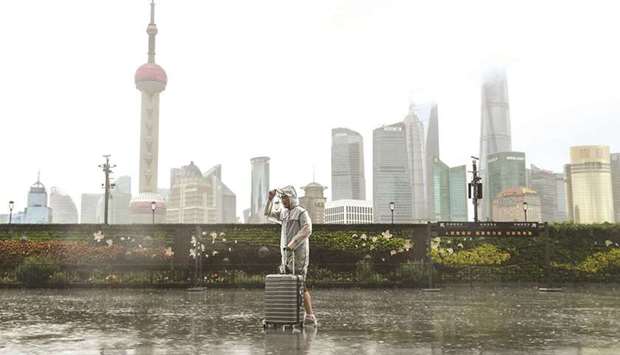 A man with luggage walks in the rain on The Bund as Typhoon In-fa approaches Shanghai, China, yesterday.