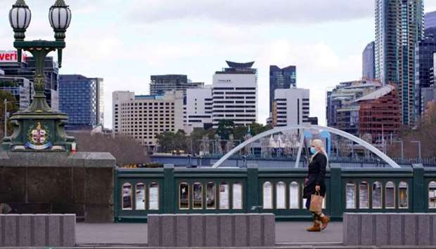 A lone woman, wearing a protective face mask, walks across an unusually quiet city centre bridge on the first day of a lockdown as the state of Victoria looks to curb the spread of a coronavirus disease (Covid-19) outbreak in Melbourne, Australia,