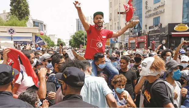 Demonstrators gather in front of police officers standing guard during an anti-government protest in Tunis, yesterday.