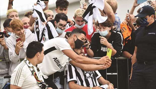 Juventusu2019 Cristiano Ronaldo wearing a protective face mask takes a photo with fans as he arrives at Juventus medical centre in Turin, Italy, yesterday. (Reuters)