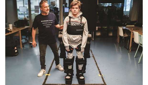 Jean-Louis Constanza, Chief Business and Clinical Officer at French company Wandercraft, helps his 16-year-old son Oscar use a robot exoskeleton in Paris. (Reuters)