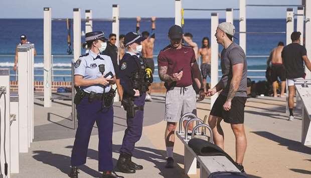 Patrolling police officers check ID information of people working out at a Bondi Beach outdoor gym area during a lockdown in Sydney.