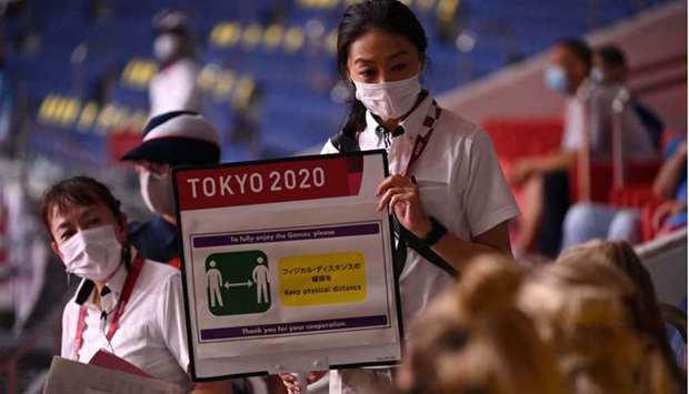 An IOC volunteer shows a sign to Sweden's delegation members reminding to respect the Covid-19 countermeasures during the men's preliminary round group B handball match between Sweden and Portugal of the Tokyo 2020 Olympic Games at the Yoyogi National Stadium in Tokyo. AFP