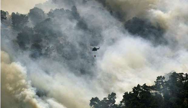 A Lebanese army helicopter drops water on a forest fire in the Qubayyat area of northern Lebanon's remote Akkar region yesterday.