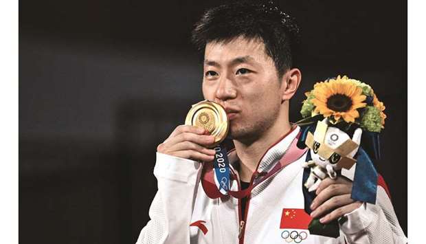 China's Ma Long kisses his medal during the men's singles table tennis medal ceremony at the Tokyo Metropolitan Gymnasium during the Tokyo 2020 Olympic Games in Tokyo on July 30, 2021. (AFP)