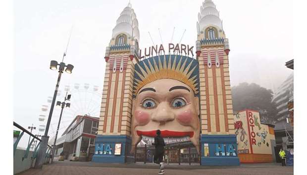 A woman jogs in front of the Luna Park in Sydney yesterday, after the park was closed to avoid the spread of the Delta Covid-19 variant.