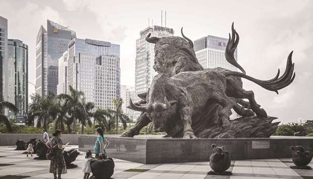 People stand in front of a sculpture of bulls at the entrance to the Shenzhen Stock Exchange building in China. A government crackdown on sectors ranging from education to technology wiped out about $1tn off Chinese shares listed on the mainland, in Hong Kong and the US over the past week.