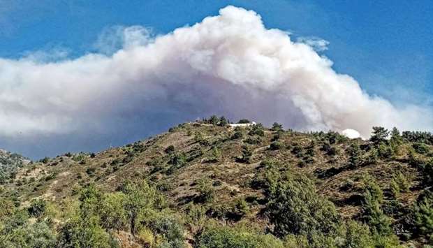 A picture taken from near the village of Farmakas in the Nicosia district of Cyprus, shows heavy smoke billowing from behind the mountains as a giant fire rages in the Larnaca district of the island. AFP