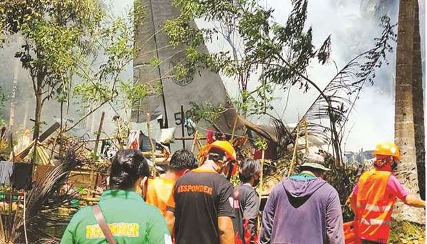 Rescue workers arrive as smoke billows from the wreckage of a Philippine Air Force C-130 transport plane after it crashed yesterday near the airport in Jolo town, Sulu province on the southern island of Mindanao.