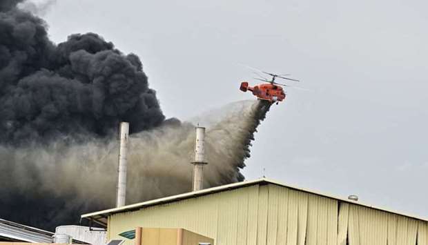 A helicopter dumps water onto the site of an explosion and fire at a plastics factory on the outskirts of Bangkok