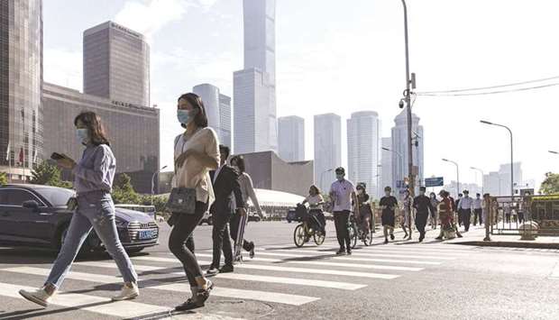 Pedestrians walk across a road in the central business district in Beijing. Financial strains among Chinese property developers are hurting the Asian high-yield debt market, where the companies account for a large chunk of bond sales.