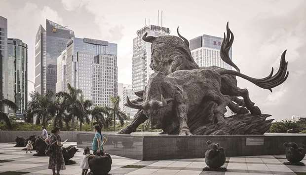 People stand in front of a sculpture of bulls at the entrance to the Shenzhen Stock Exchange building. The Composite index closed up 0.4% to 3,534.32 points yesterday.