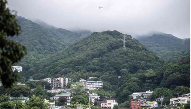A helicopter flies over the scene of a landslide (centre R) following days of heavy rain in Atami in Shizuoka Prefecture