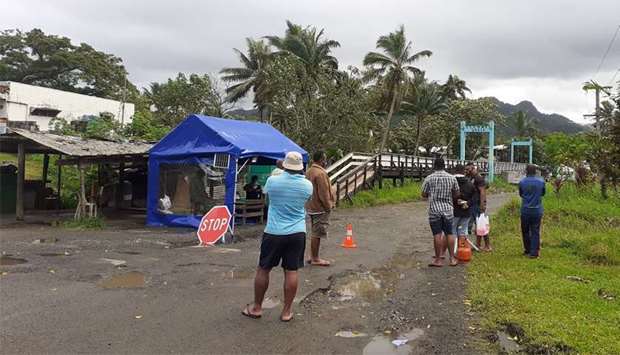 People wait at the entrance to a village settlement to deliver food to relatives that are in lockdown as an outbreak of the coronavirus disease (Covid-19) affects Lami, Fiji