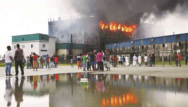 People look on as flames rise after a fire broke out at a Hashem Foods factory in Rupganj, Narayanganj district, on the outskirts of Dhaka, Bangladesh, on Friday..