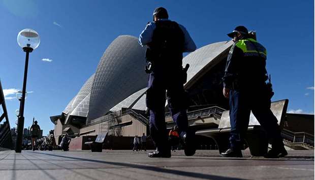 Police officers patrolling in front of the Opera House, usually packed with visitors, as a lockdown in Australia's largest city Sydney