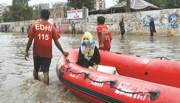 A woman sits in a rubber boat as volunteers pull through a flooded road during the monsoon season in Karachi yesterday. (Reuters)