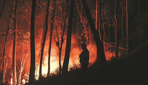 A silhouette of a firefighter standing in the forest is pictured during a wildfire at Casais do Vento in Alvaiazere yesterday. (AFP)