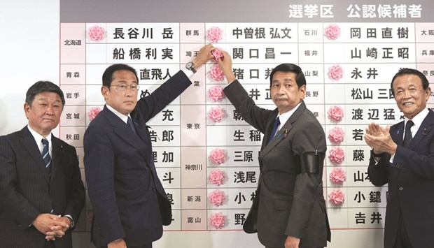 Japanu2019s Prime Minister and the President of the Liberal Democratic Party (LDP) Fumio Kishida (second left) places a red paper rose on a LDP candidateu2019s name to indicate the victory in the upper house election, along with his party executives at the partyu2019s  headquarters in Tokyo, yesterday.