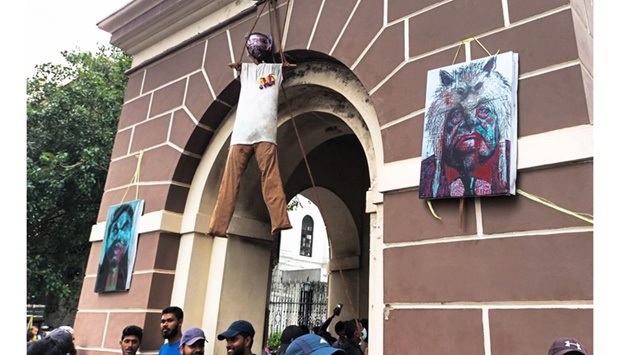 Activists stand under an effigy of Sri Lanka's President Gotabaya Rajapaksa, hanging from a clock tower near his official residence, in Colombo on July 10. AFP