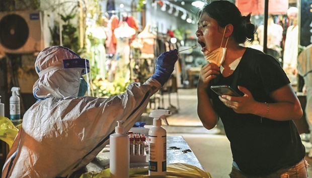 A health worker takes a swab sample from a woman to test for the Covid-19 coronavirus in the Huangpu district of Shanghai, yesterday.
