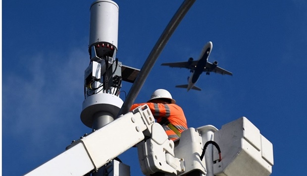 A contractor installs 5G cellular equipment on a light pole as a Delta Air Lines airplane lands at Los Angeles International Airport. The global aviation industry continues to voice concerns over the roll out of 5G networks in many countries including the United States due to the potential interference with aircraft instrument systems.