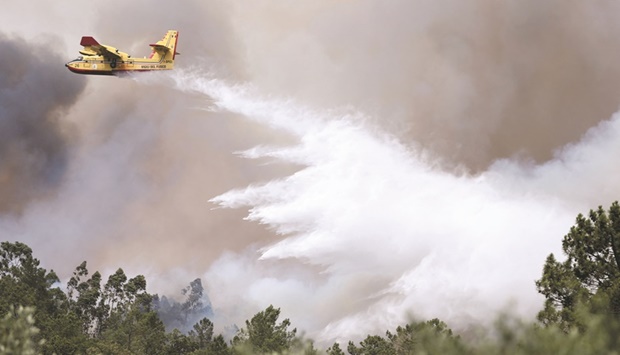 A firefighting aircraft works yesterday to contain a forest fire in Leiria, Portugal.
