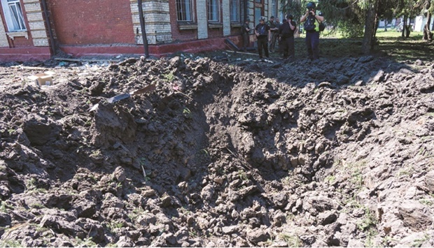 Police experts examine a crater after a Russian missile strike near a school on the outskirts of Kharkiv yesterday.