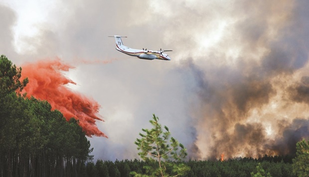 A firefighting plane drops flame retardant to extinguish a fire in Guillos as wildfires continue to spread in the Gironde region of southwestern France yesterday. (Reuters)
