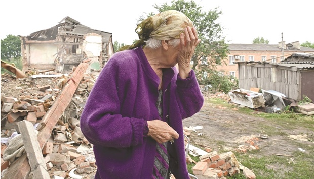 A local resident, Raisa Kuval, 82, reacts next to a damaged building partially destroyed after a shelling in the city of Chuguiv, east of Kharkiv, yesterday. AFP)