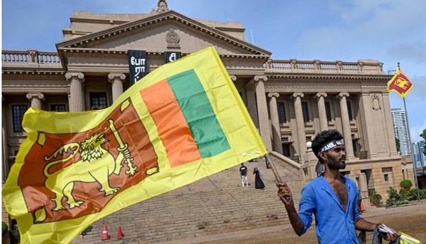 A man wears a headband with a slogan against interim Sri Lankan President Ranil Wickremesinghe as he waves the Sri Lankan national flag near the Presidential secretariat in Colombo.