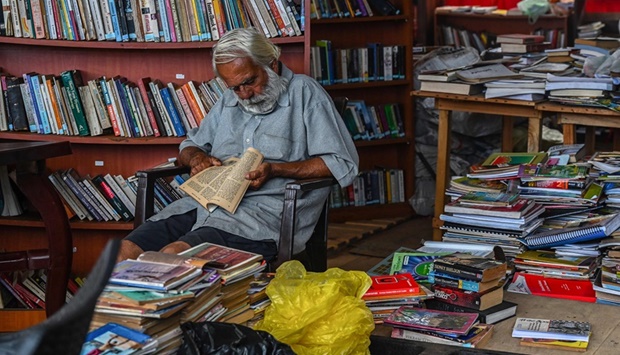 A man reads sitting at a mini library created by the demonstrators at the Galle face protest area near the Presidential secretariat in Colombo, yesterday.