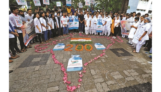 Medical personnel and students hold placards as they stand around a formation to celebrate India administering 2bn vaccine doses against the coronavirus (Covid-19) disease, at a hospital in Ahmedabad.
