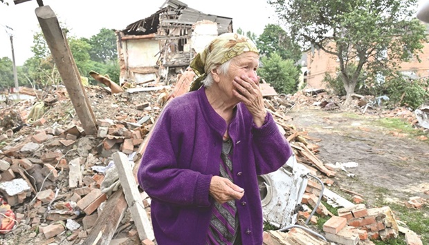Local resident, Raisa Kuval, 82, reacts next to a damaged building after a shelling in the city of Chuguiv, east of Kharkiv.