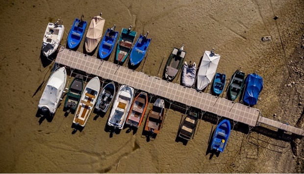 An aerial view shows boats in the dry bed of Brenets Lake (Lac des Brenets), part of the Doubs River, a natural border between eastern France and western Switzerland, in Les Brenets on July 18, 2022. The river has dried up due to a combination of factors, including geological faults that drain the river, decreased rainfall and heat waves