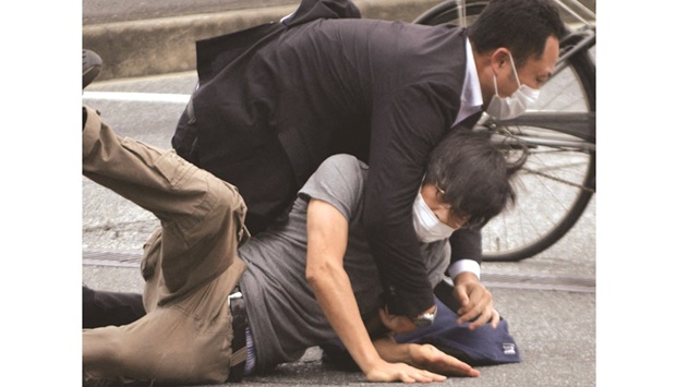 Tetsuya Yamagami, the shooter, being held by police officers at Yamato Saidaiji Station in Nara, Nara Prefecture on July 8 in this photo taken by the Yomiuri Shimbun newspaper.
