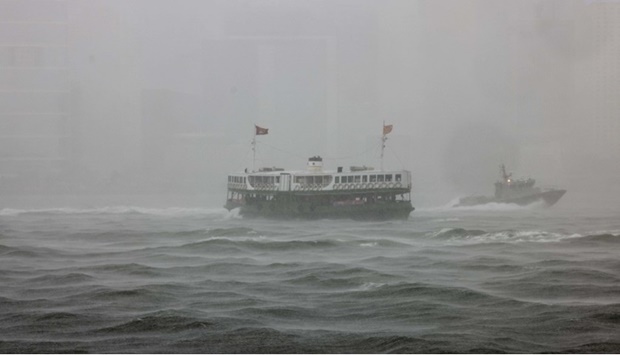 A Star Ferry (C) crosses Victoria Harbour, with the Hong Kong skyline blanketed in heavy rain, as severe Tropical Storm Chaba passes close to Hong Kong on July 1, 2022.