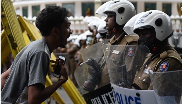 A demonstrator interacts with Police special task force personnel (R) standing guard while blocking a road as demonstrators take part in a protest march against Sri Lankan President Ranil Wickremesinghe towards the Presidential secretariat office in Colombo. Arun Sankar/AFP