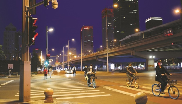 People wearing face masks ride shared bicycles on the street in the Central Business District (CBD) in Beijing (file).