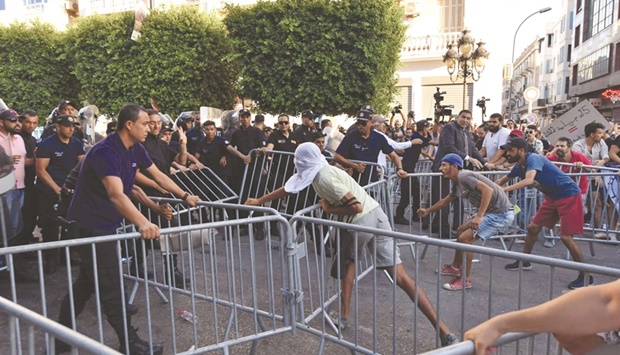 Tunisian protesters scuffle with the police as they remove metallic barriers yesterday, during a demonstration along Habib Bourguiba avenue in the capital Tunis, against their president and the upcoming July 25 constitutional referendum.