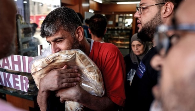A man walks out of a bakery clutching a bag of subsidised flatbread, as others continue to wait in a queue, in the Lebanese capital Beirut on July 29, 2022, amid a shortage of wheat supplies.