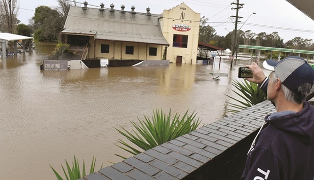 A man films flooded streets in the Camden suburb of Sydney yesterday.