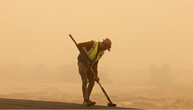 A worker sweeps a road during a sandstorm in Iraq's Diyala province, on July 3, 2022.