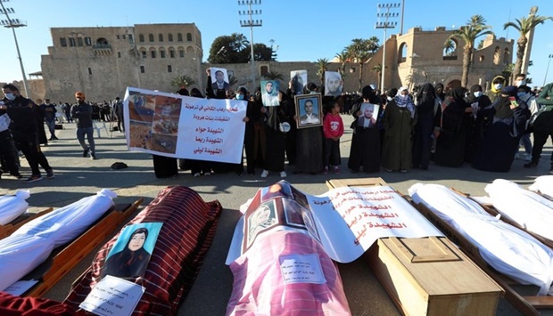 Mourners show portraits near bodies which were exhumed from a mass grave in Tarhouna, before getting reburied in Tripoli, Libya January 22, 2021. REUTERS
