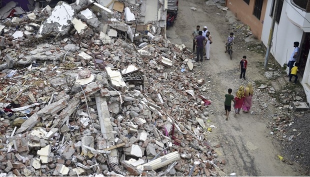 In this picture taken on June 23, 2022, people stand next to the rubble of activist Javed Mohammad's house in Allahabad.