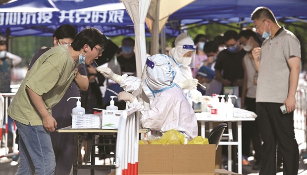 A health worker gets a swab sample from a man to be tested for Covid-19 at a swab collection site in Beijing yesterday.