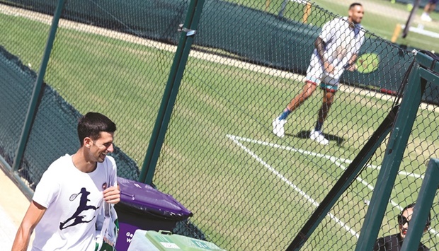 Serbiau2019s Novak Djokovic (left) walks past as Australiau2019s Nick Kyrgios trains at The All England Lawn Tennis Club yesterday ahead of their Wimbledon final. (Reuters)
