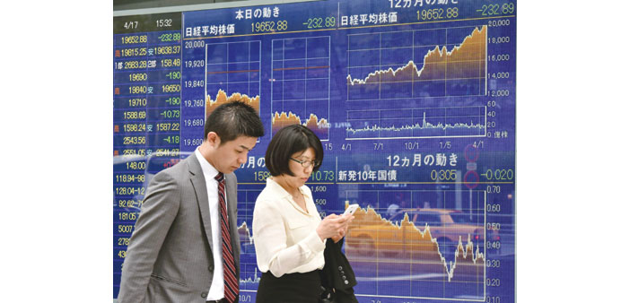 Pedestrians pass before a share prices board in Tokyo. Japanese stocks closed down 232.89 points to 19,652.88 yesterday.