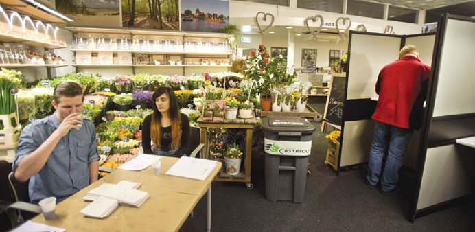 Early voters cast their ballot at a polling booth set up in a flower shop during the Dutch municipal council elections at the railway station of Castr